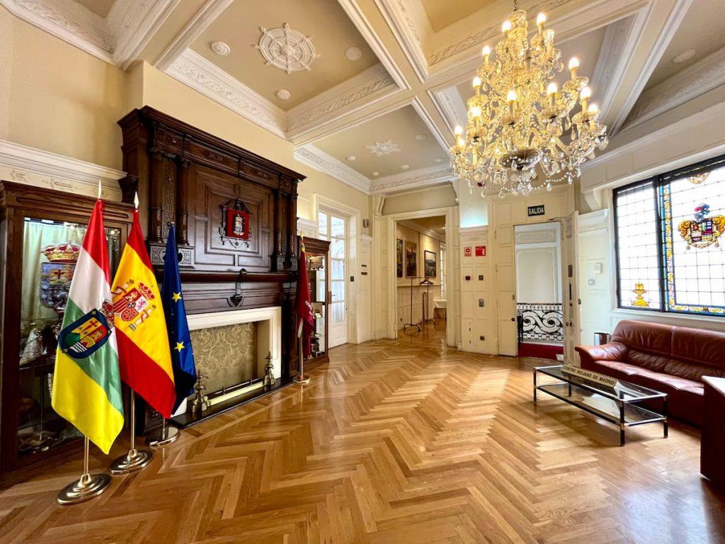 Interior del Centro Riojano de Madrid con banderas, chimenea y lámpara de araña